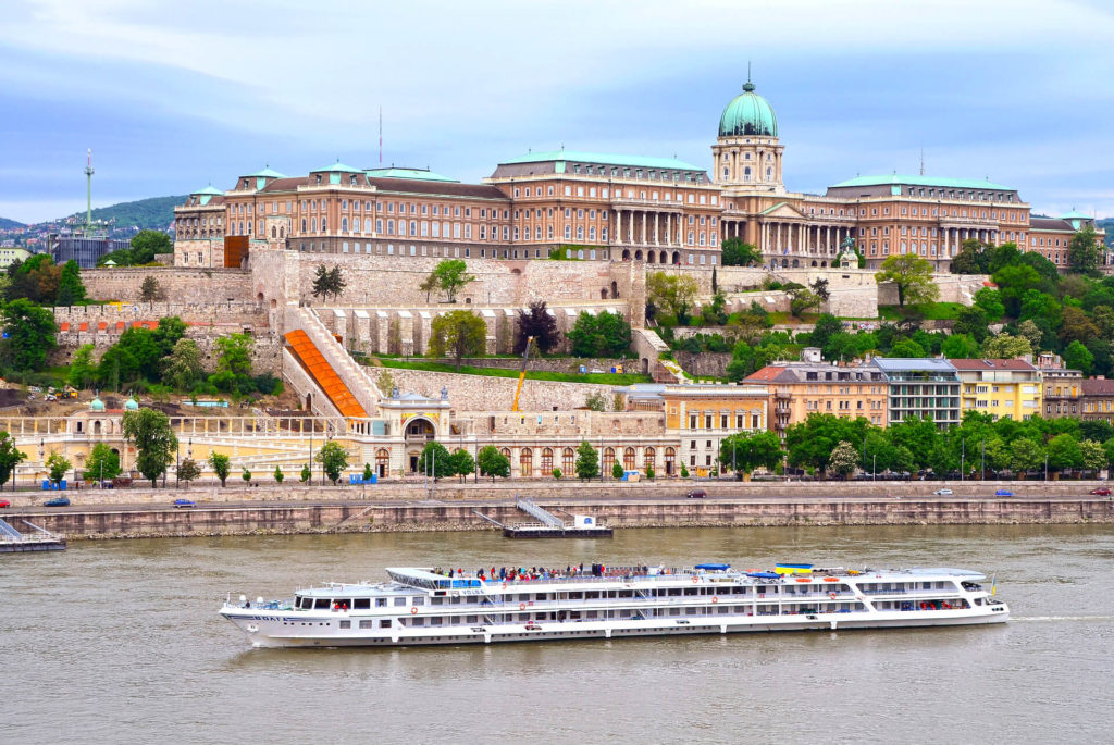 Photo showing the castle district in Budapest, the royal palace and a cruise ship passing by the Danube river